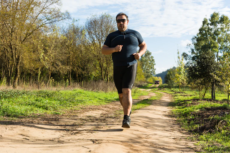 A man in black workout gear runs outdoors.