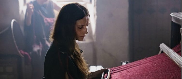 Una mujer (Penélope) teje en un telar.