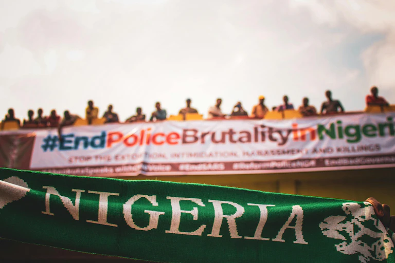 Row of people standing on a bridge with banners hanging from it