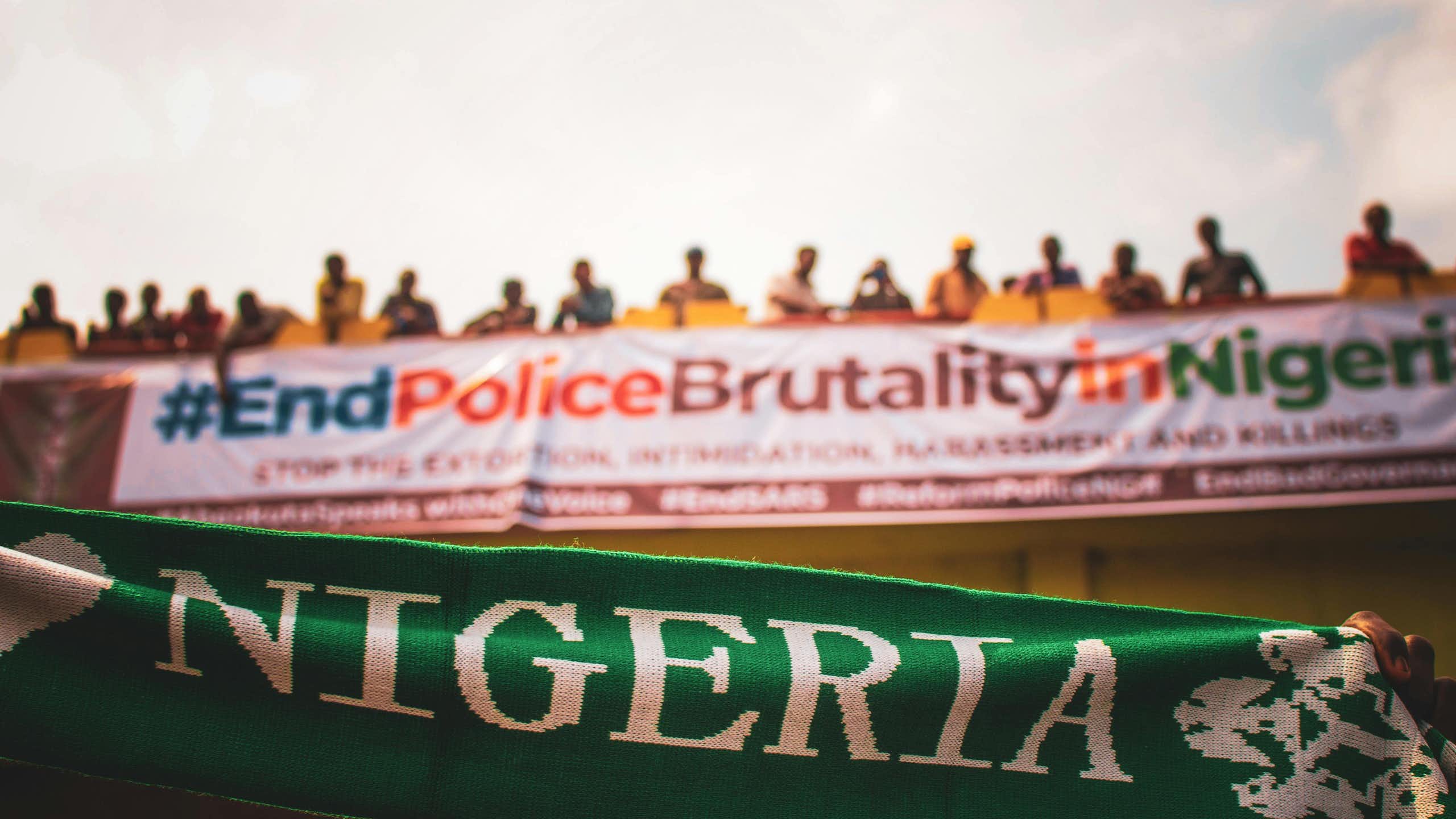 Row of people standing on a bridge with banners hanging from it