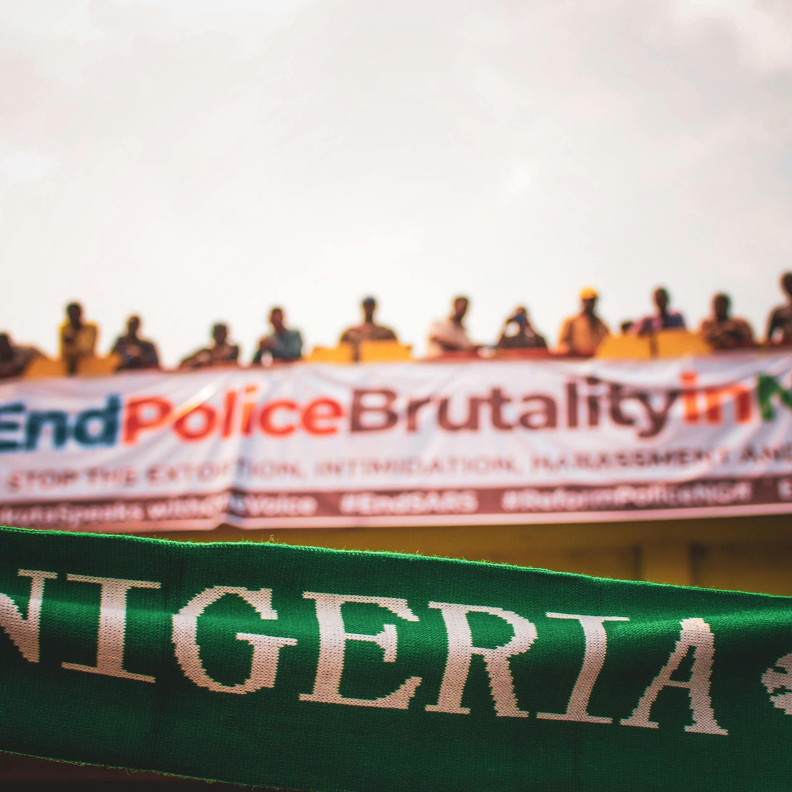 Row of people standing on a bridge with banners hanging from it