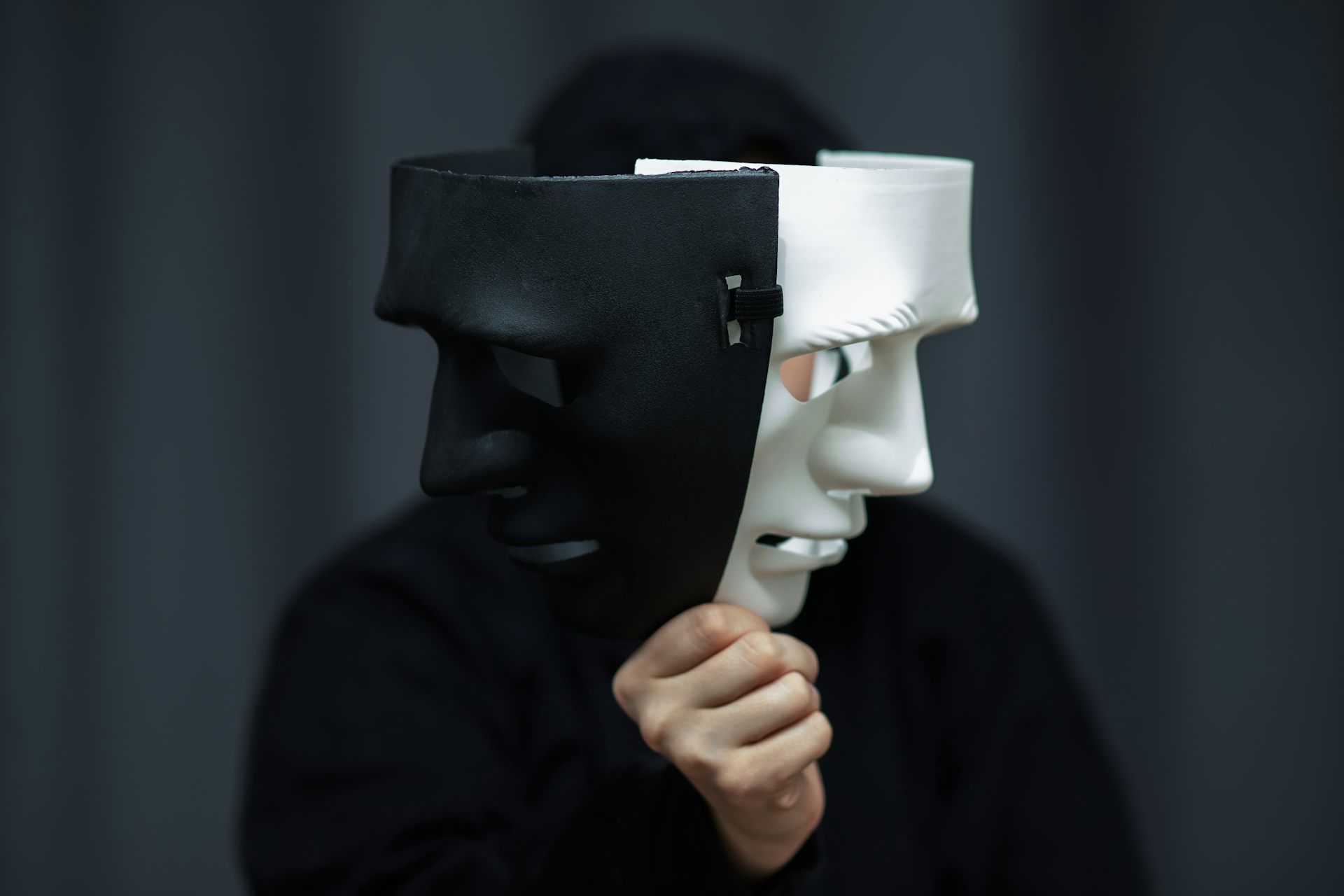A person holding up two sinister masks
