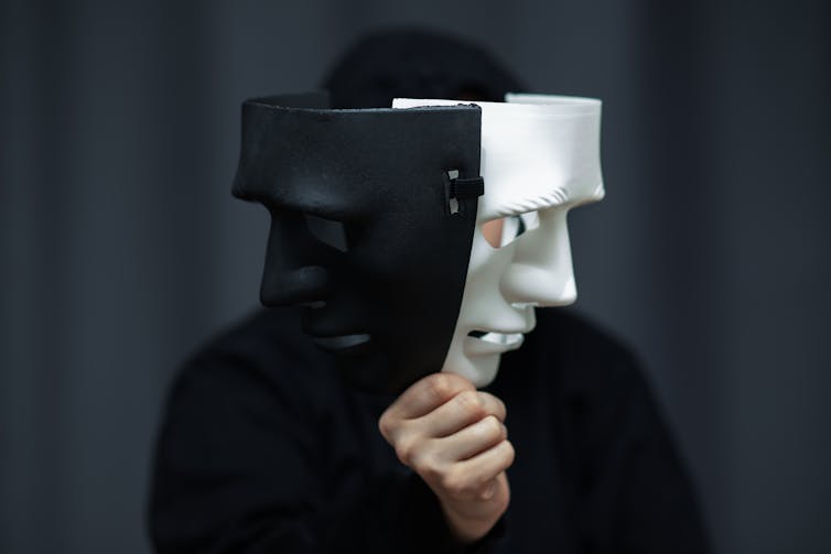 A person holding up two sinister masks