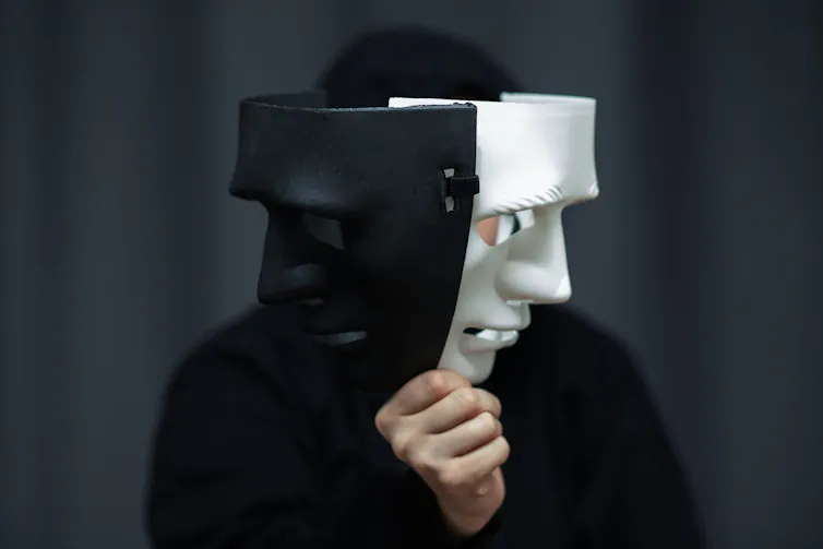 A person holding up two sinister masks