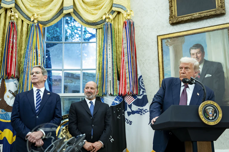 us president donald trump standing at a lectern while treasury secretary scott bessent and commerce secretary howard lutnick look on.