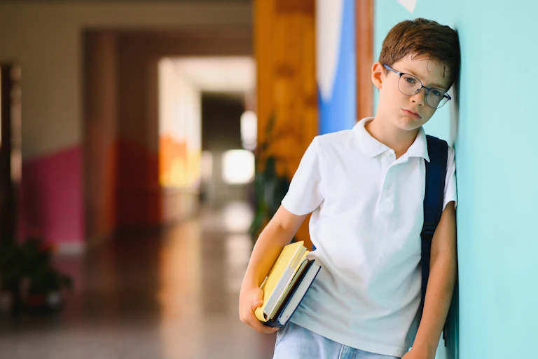 Boy looking sad in school corridor