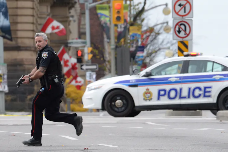 Un policía corre por una calle de la ciudad con el arma en la mano.