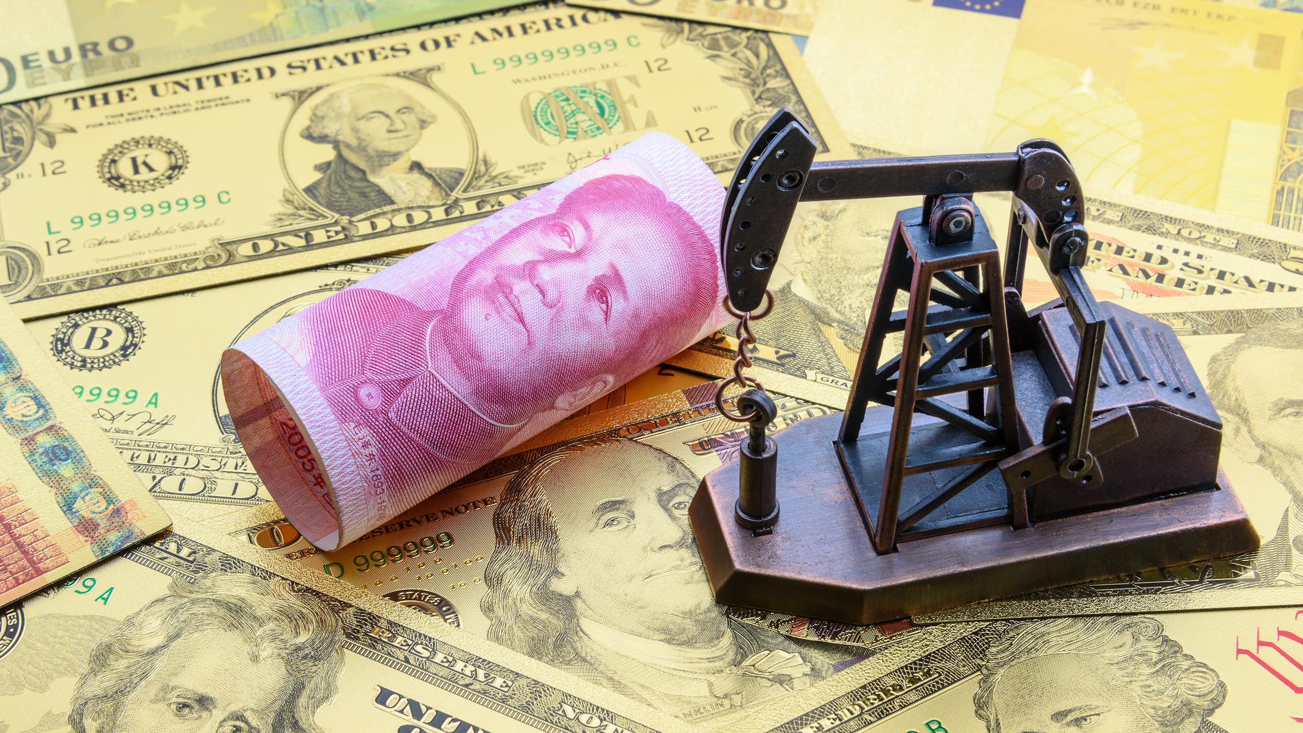Chevalet de pompage de pétrole sur des billets de dollars, d'euros et de yuans.