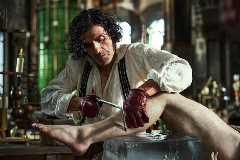 Oscar Isaac as Victor Frankenstein cutting a leg