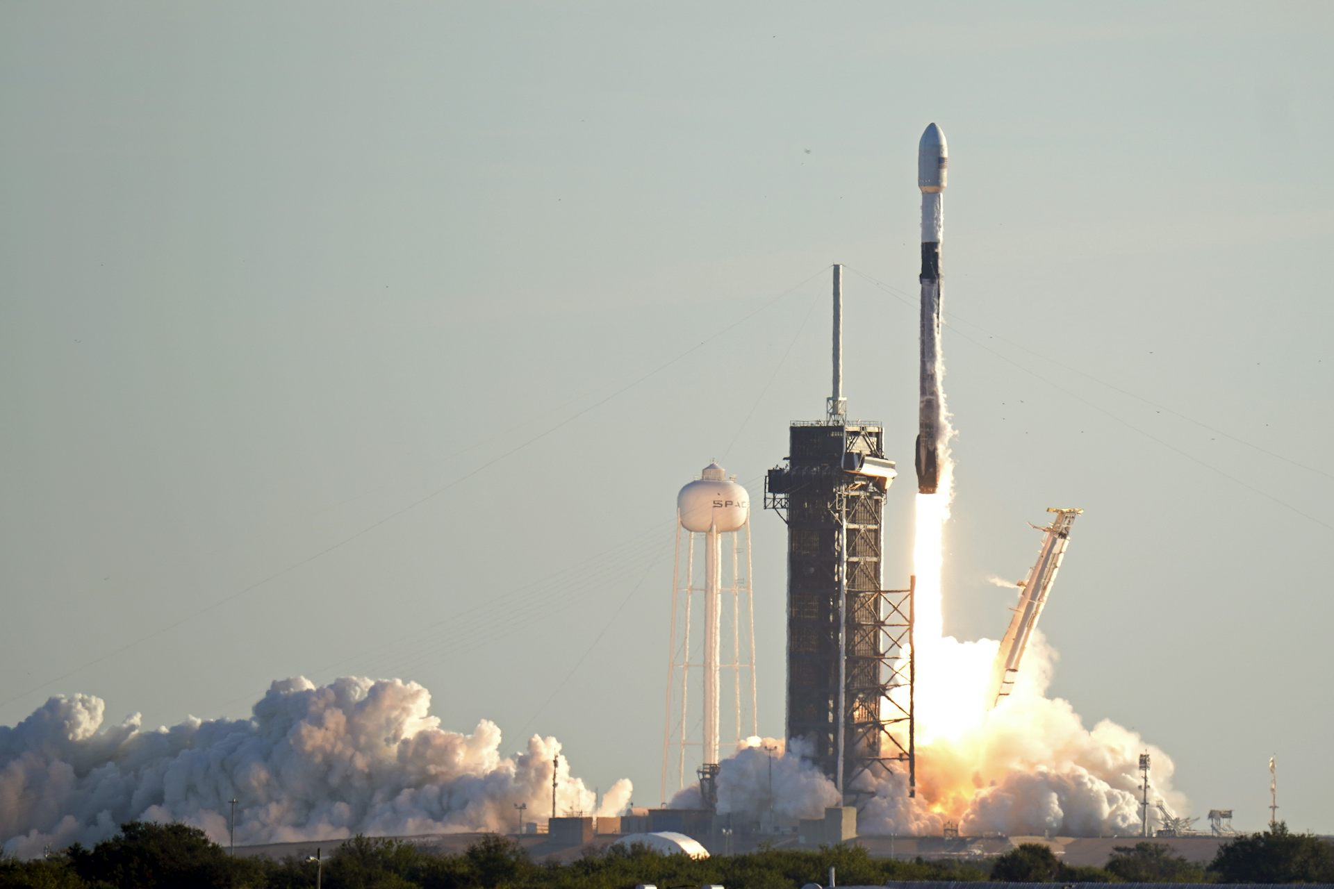 A rocket launching from a structure, with a plume of smoke beneath it.