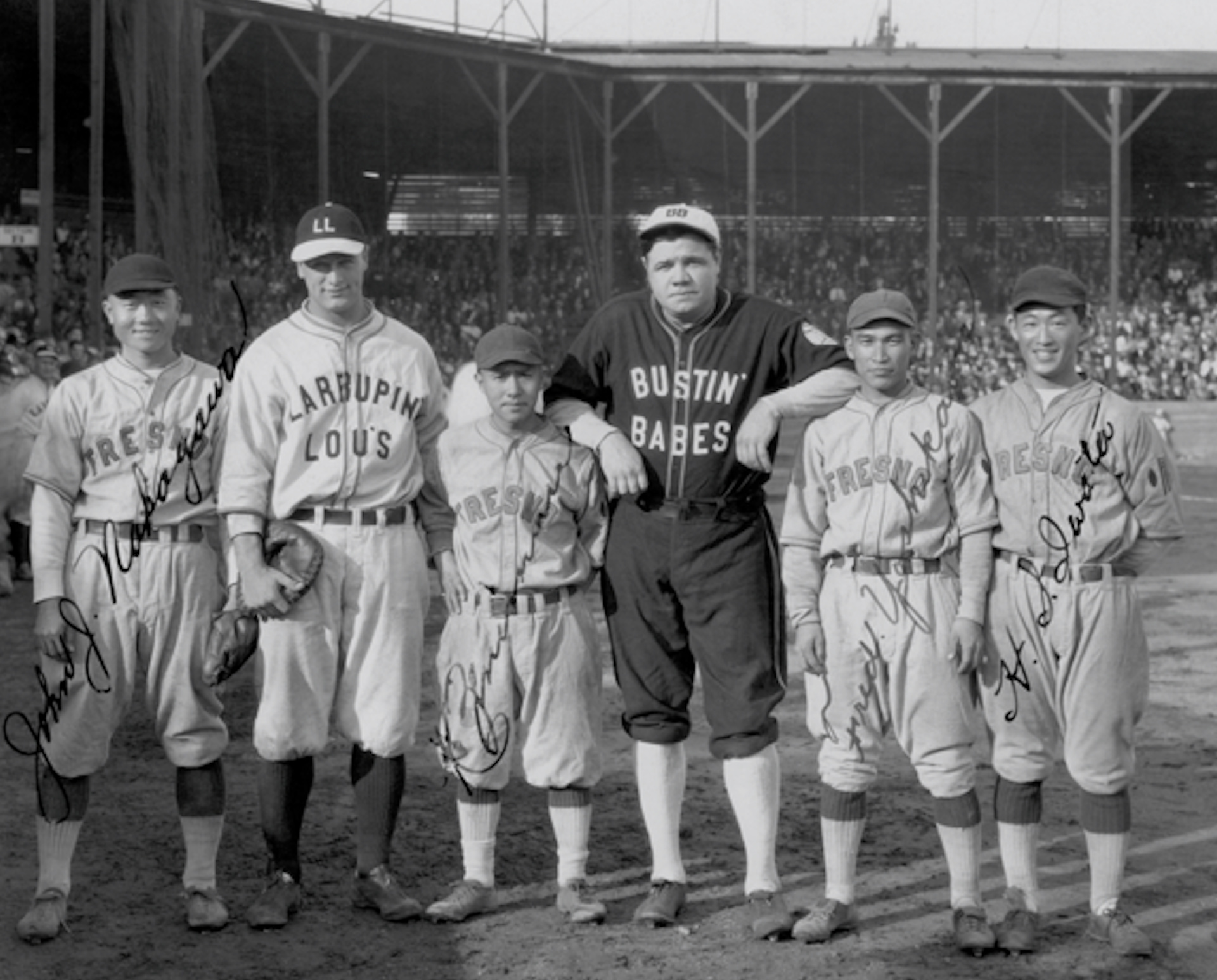 A black and white photograph of six baseball players – four Asian Americans and two white Americans – posing on a diamond while wearing baseball uniforms.