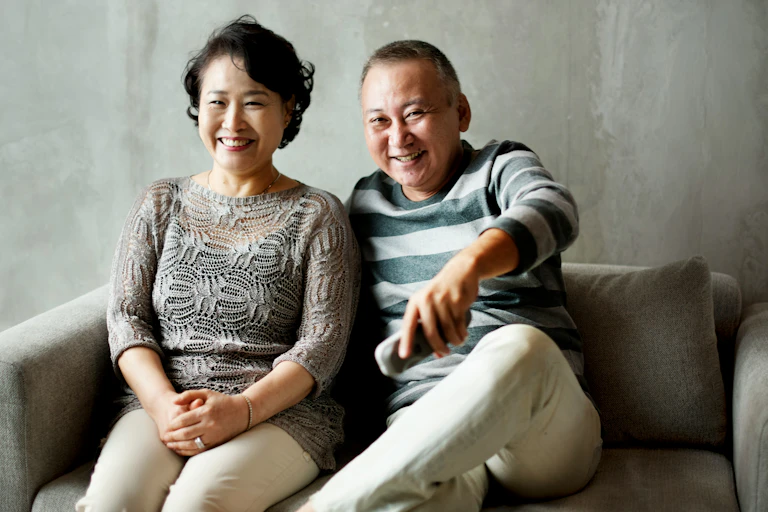 A couple sitting on a couch smiling.