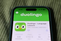 phone displays the Duolingo app with an icon of the face of a green bird