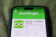 phone displays the Duolingo app with an icon of the face of a green bird