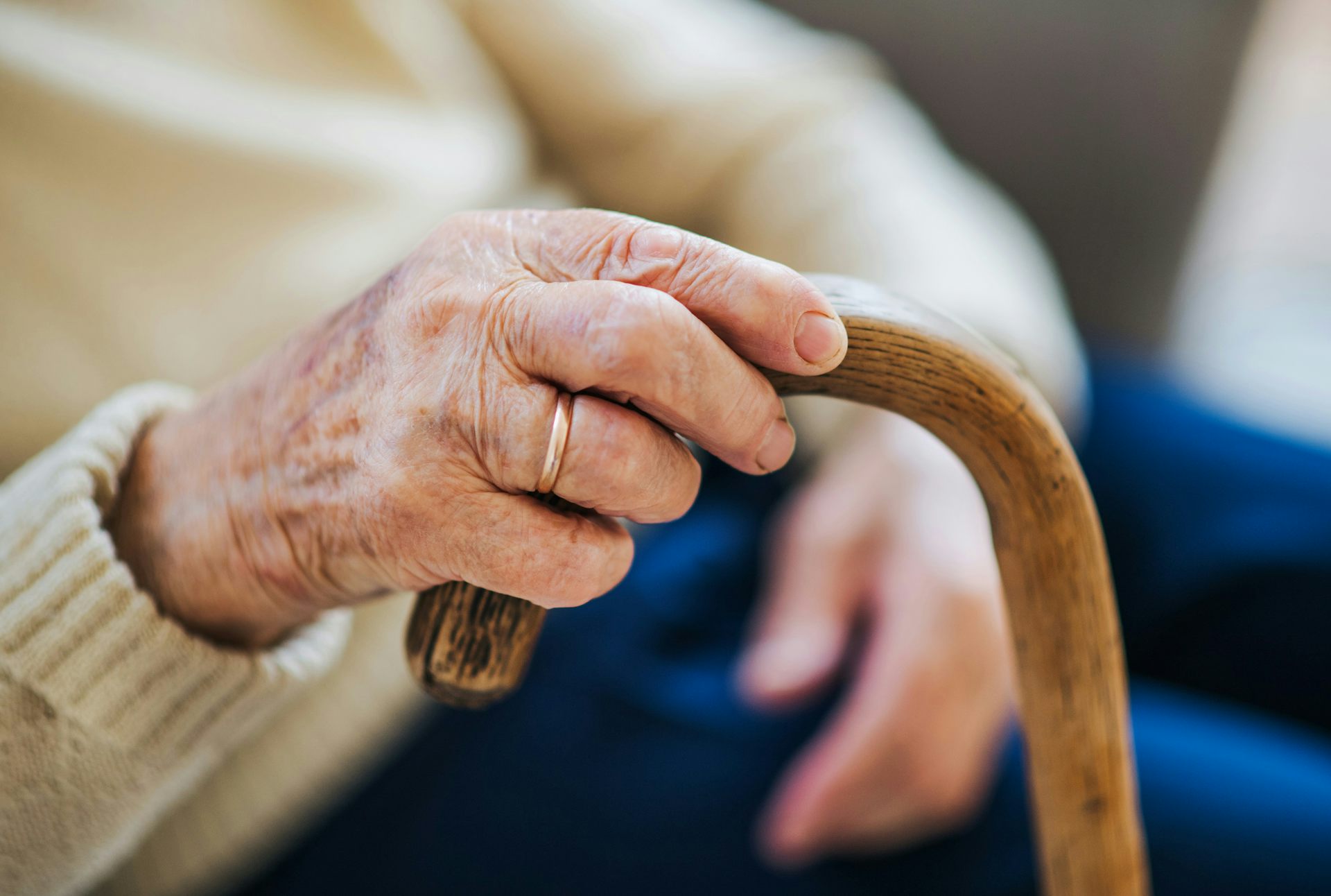Une main d’une personne âgée tient une canne