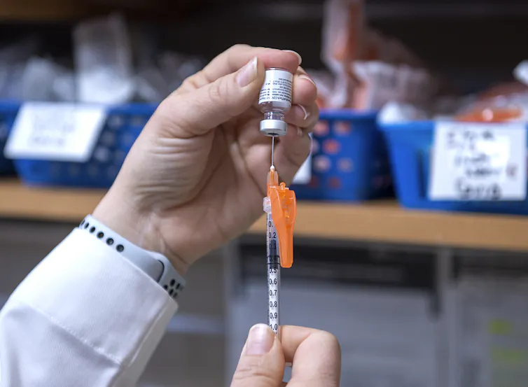 Closeup of a pair of hands filling up a needle with a vaccine
