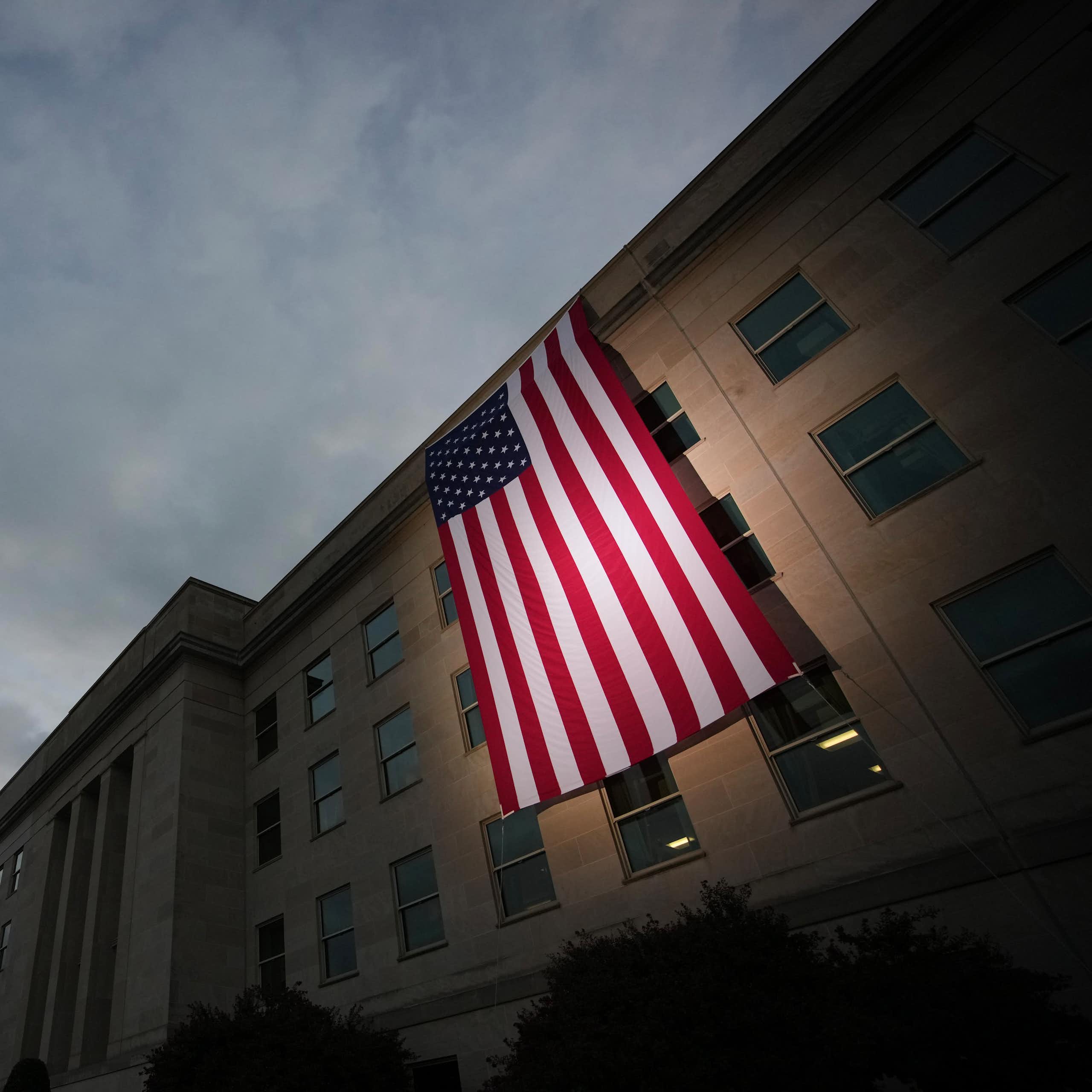 A U.S. flag is draped over a concrete building.