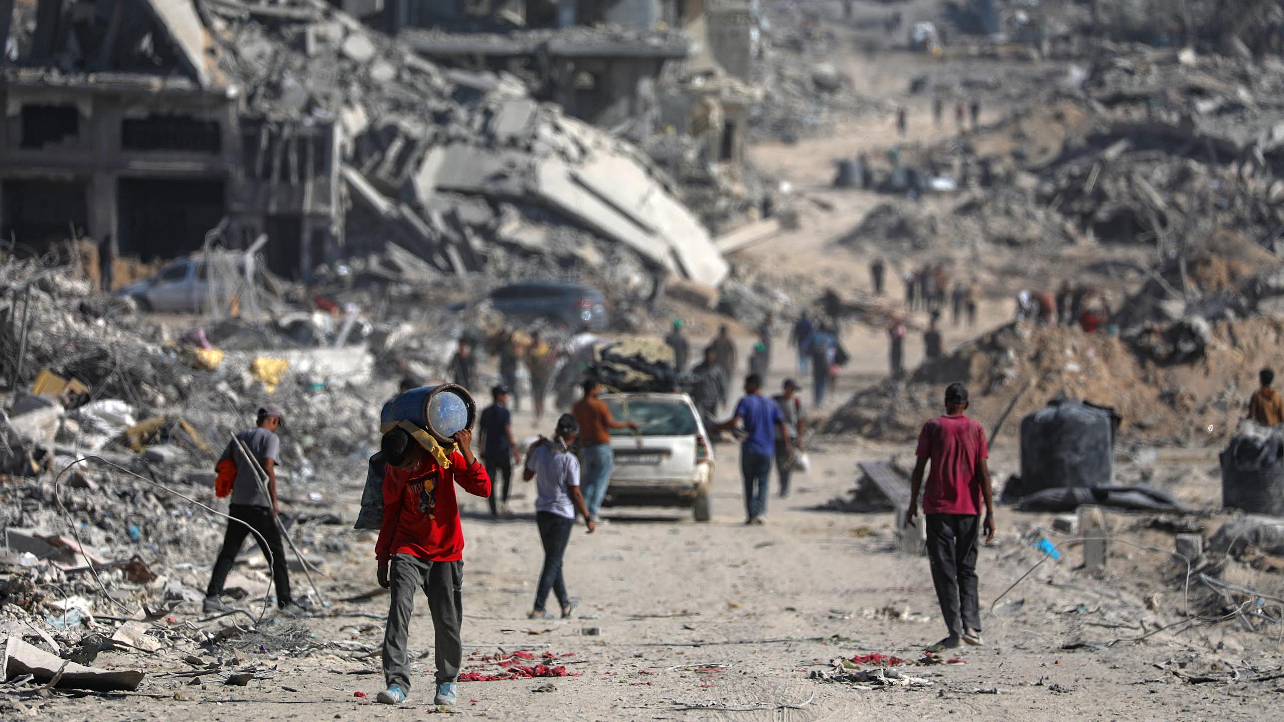 Palestinians walk along the rubble of destroyed buildings in Gaza City.