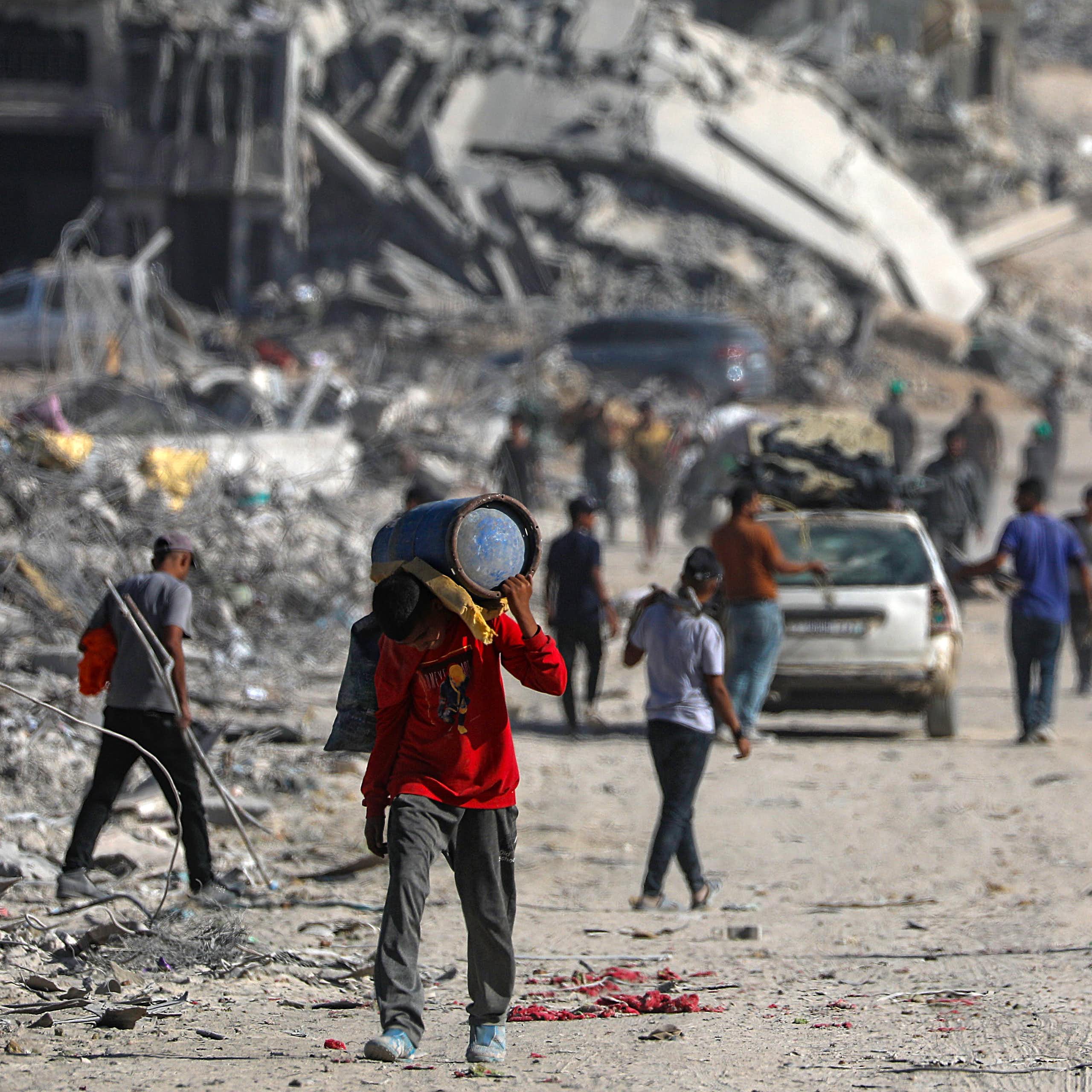 Palestinians walk along the rubble of destroyed buildings in Gaza City.