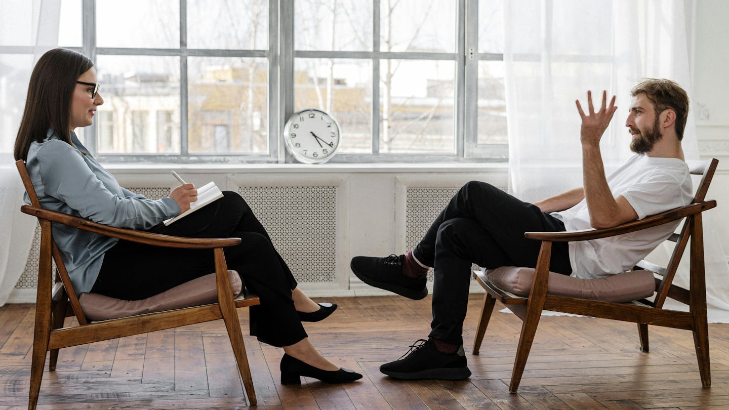 A therapist and her client talk in a well lit room.