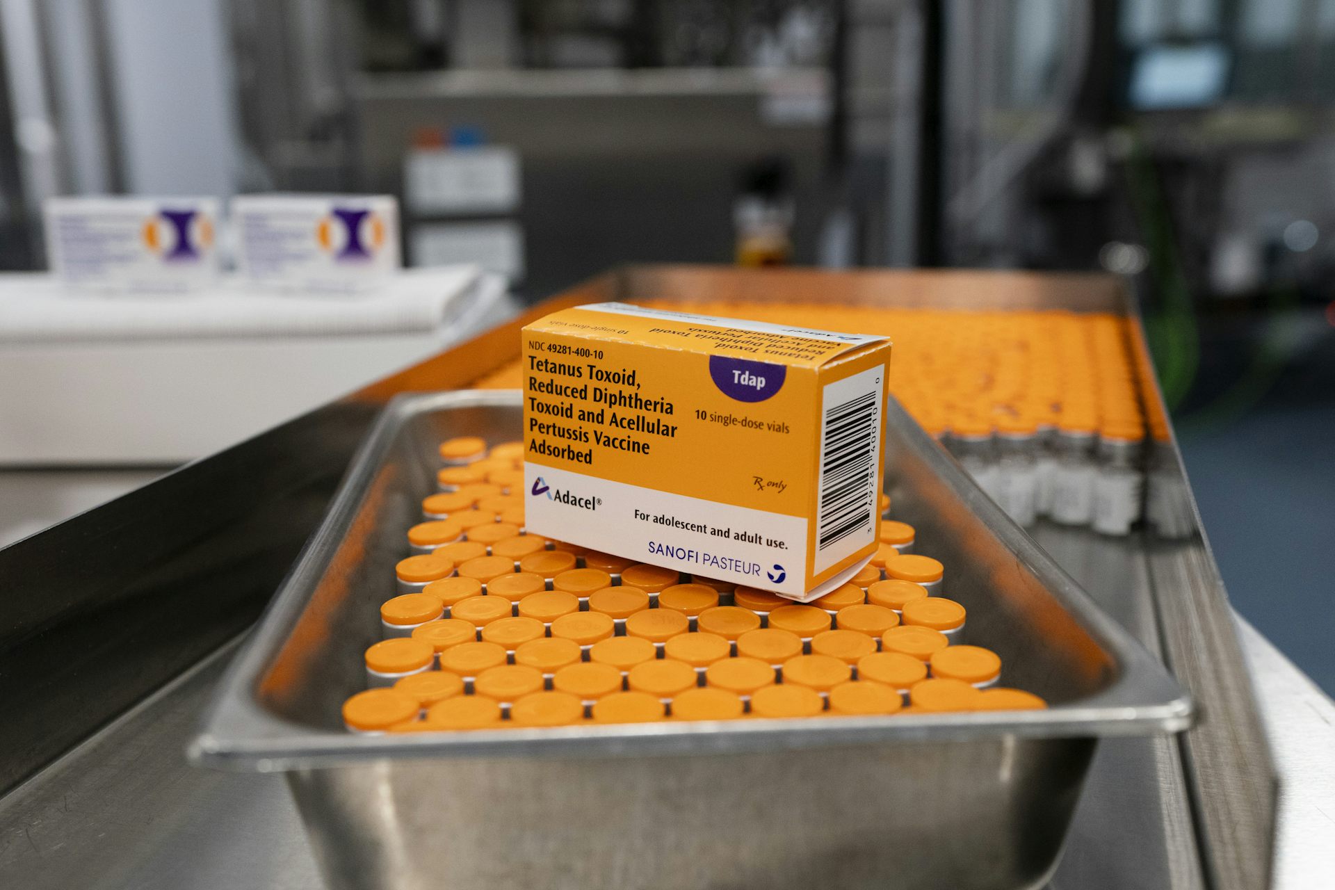 Una caja de vacunas colocada sobre una bandeja de metal llena de viales.