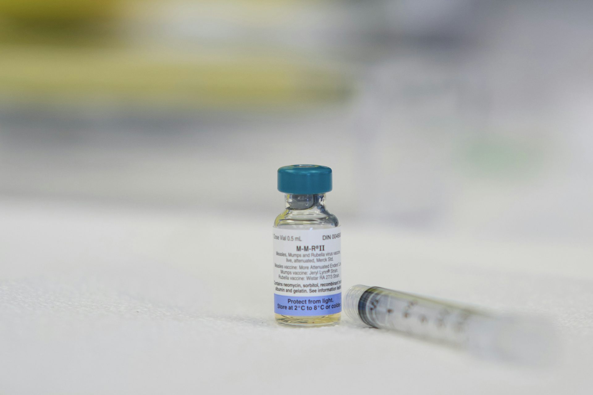 A dose of a vaccine sits beside a needle
