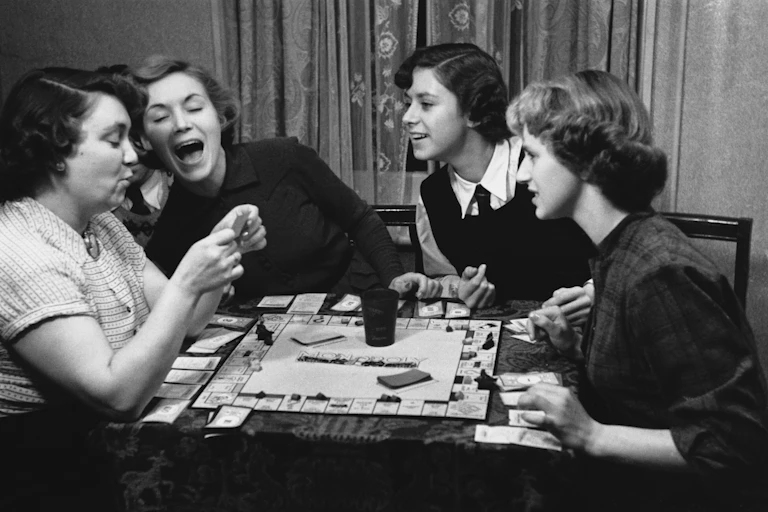 Four young women in the 1950s play Monopoly.