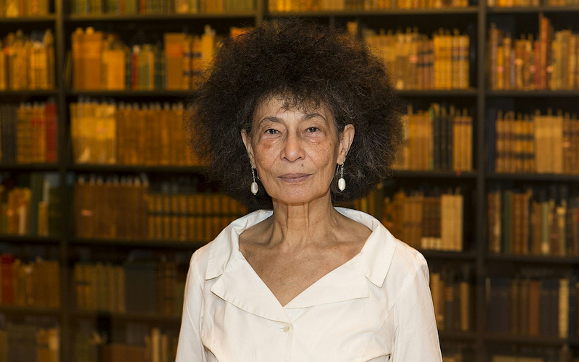 An African woman with light skin and a large Afro in a library of books.
