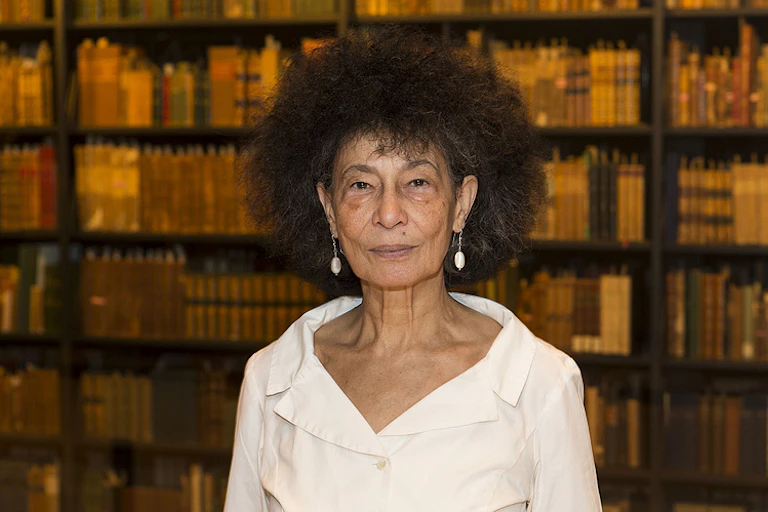 An African woman with light skin and a large Afro in a library of books.