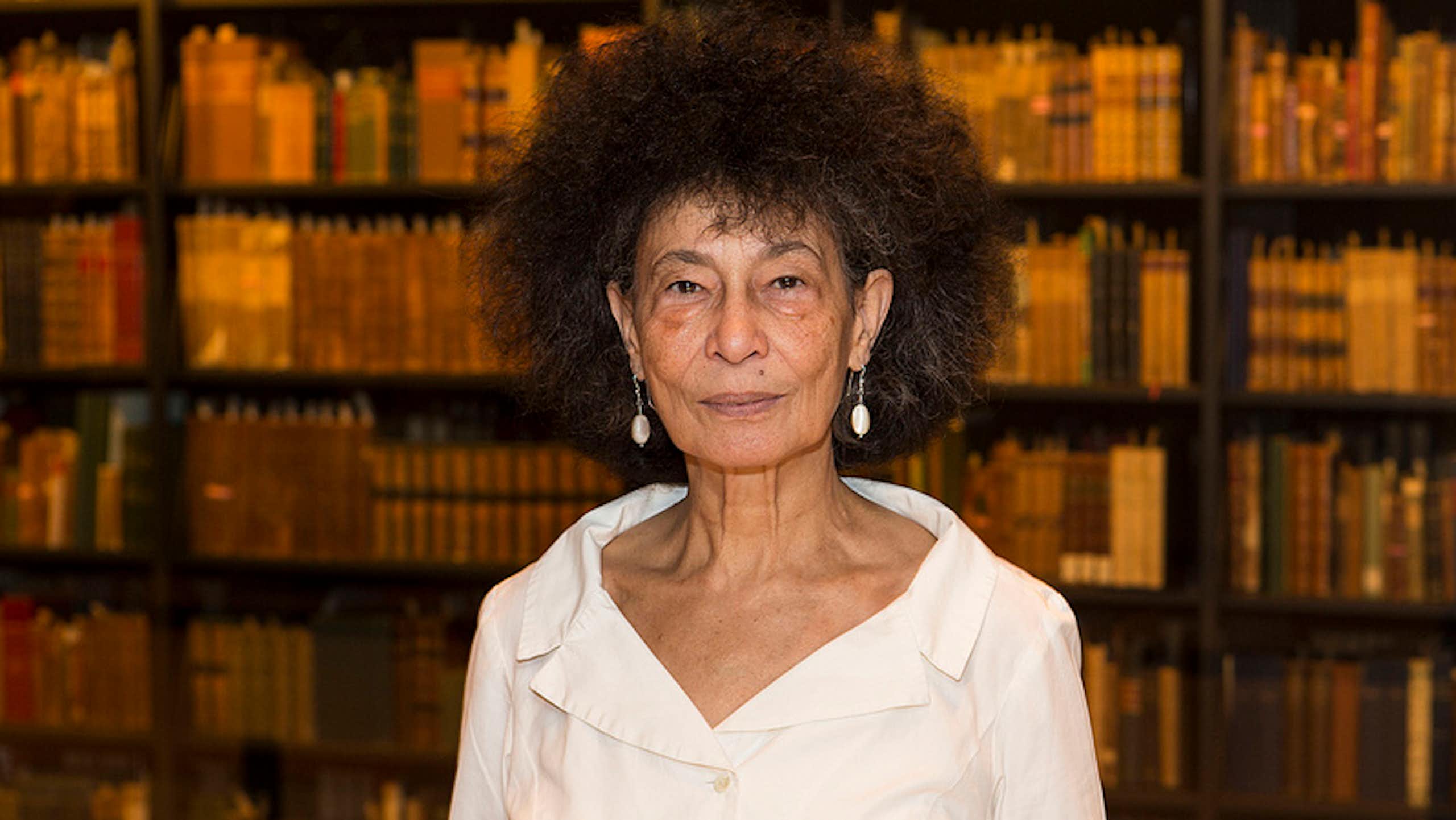 An African woman with light skin and a large Afro in a library of books.