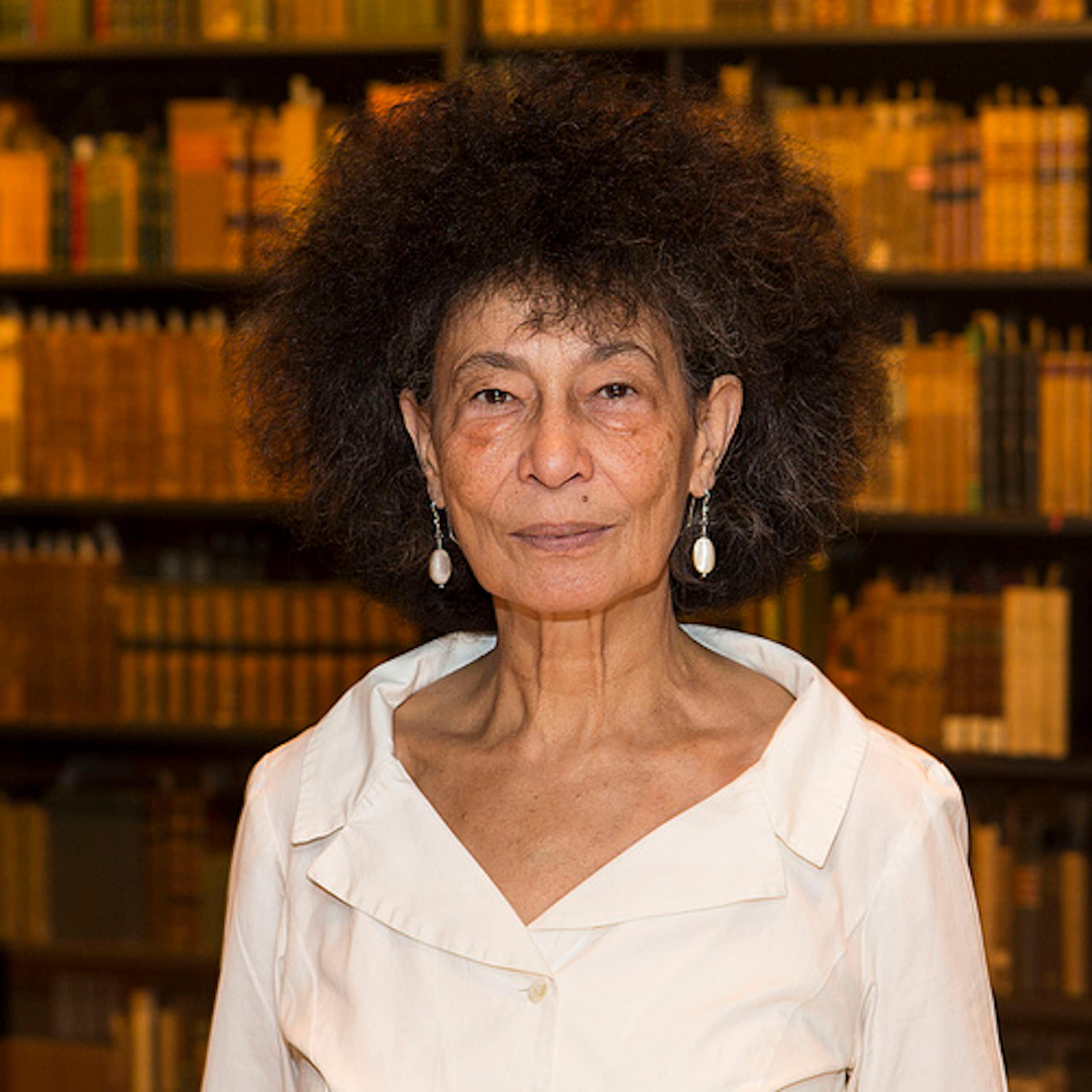 An African woman with light skin and a large Afro in a library of books.