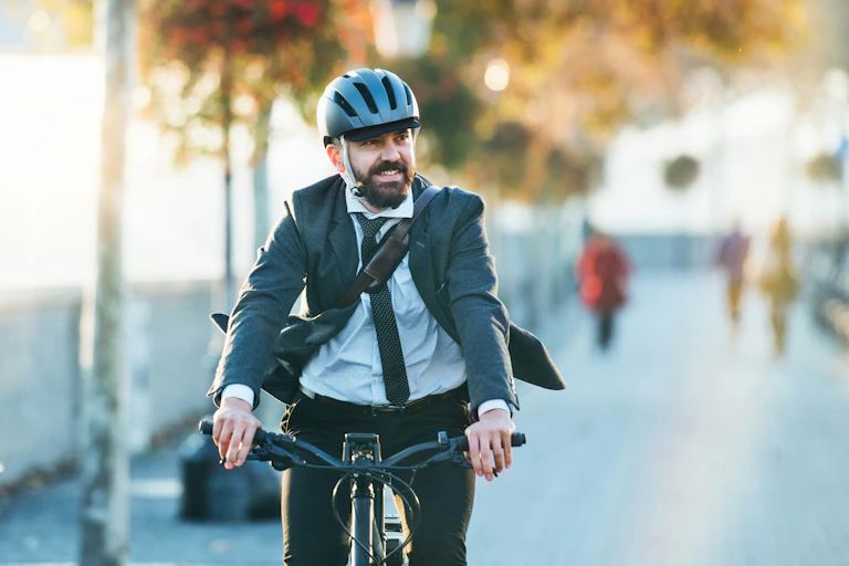 Un homme en tenue de bureau et portant un casque fait du vélo.