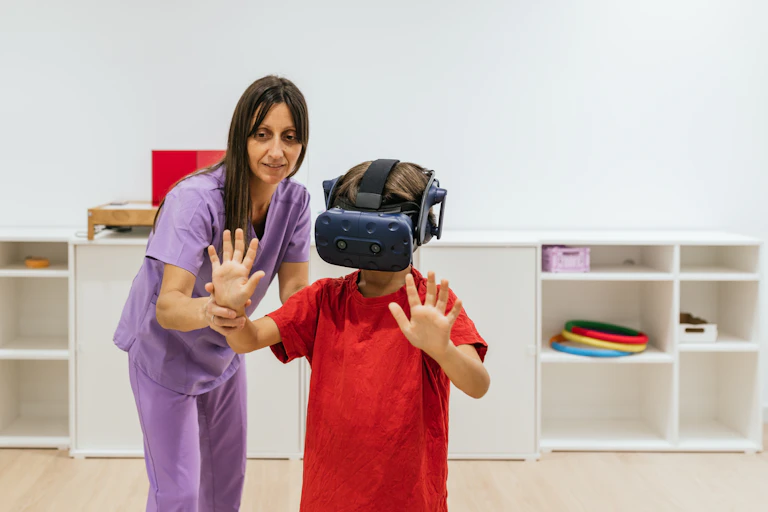 Un jeune garçon équipé d’un casque de réalité virtuelle effectue un exercice avec l’aide d’une soignante.