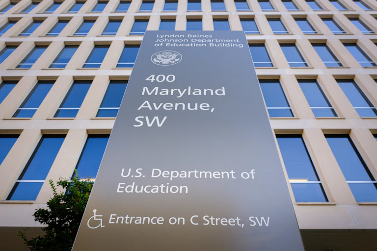 A large stone plaque says 400 Maryland Avenue, SW, U.S. Department of Education, in front of a large building with many windows.
