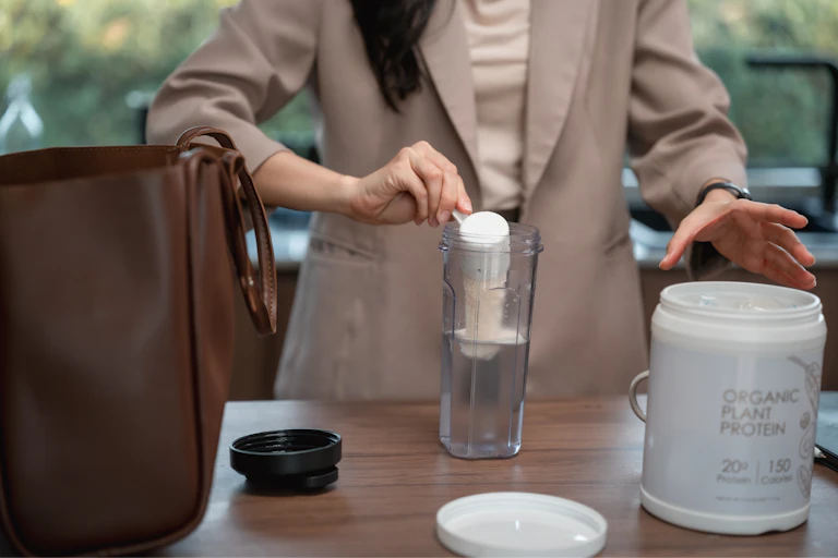 Businesswoman preparing a protein shake in her kitchen before heading to work