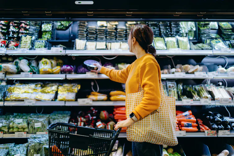A young woman picks up a package of fresh produce at the supermarket.