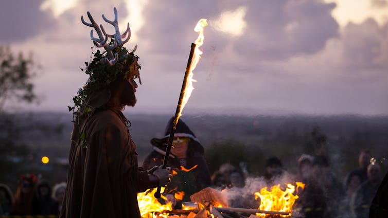 A man representing the Winter King holds a flaming sword as he takes part in a ceremony as they celebrate Samhain