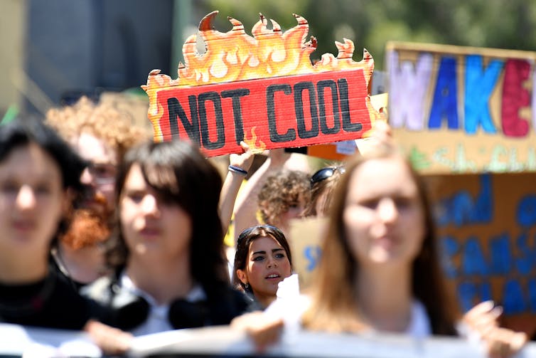 A group of young protestors holding up a sign saying not cool