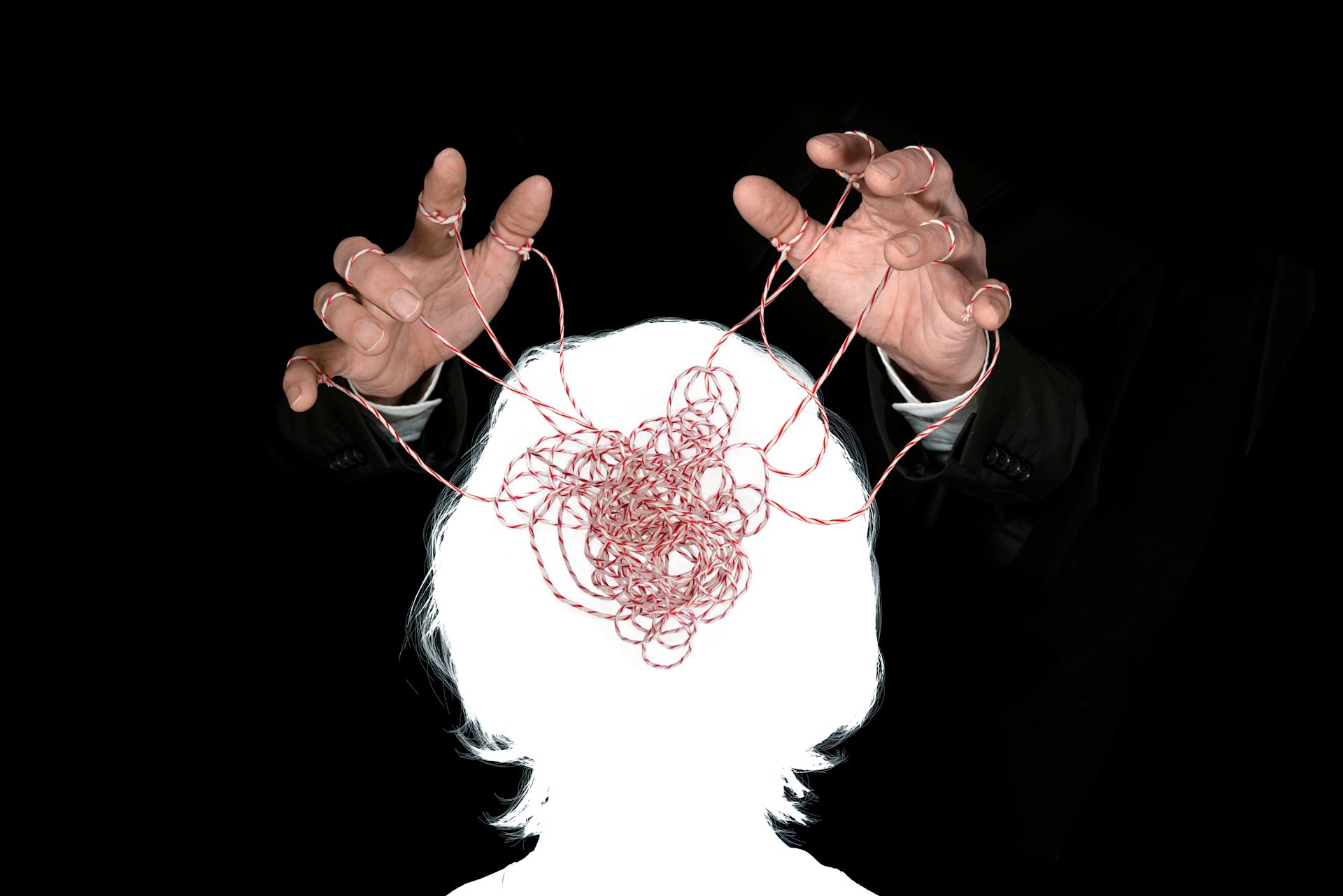 Unas manos controlan con hilos la representación de un cerebro