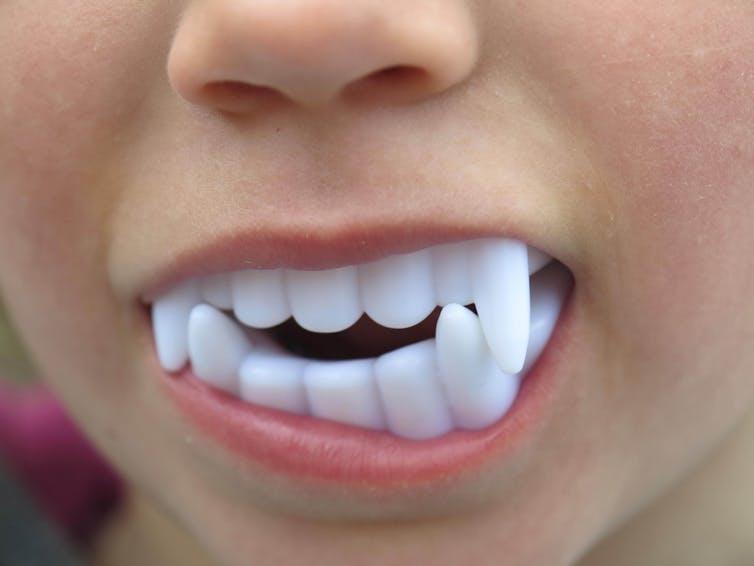 A child wearing plastic fangs.