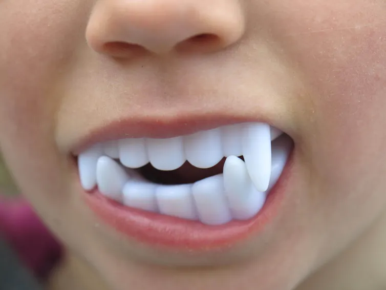 A child wearing plastic fangs.
