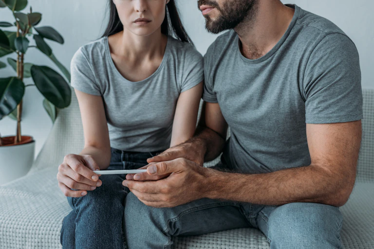 Un couple, mines sombres, consulte un test de grossesse.