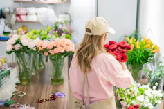 Photo d’une femme, de dos, préparant un bouquet dans une boutique de fleurs.