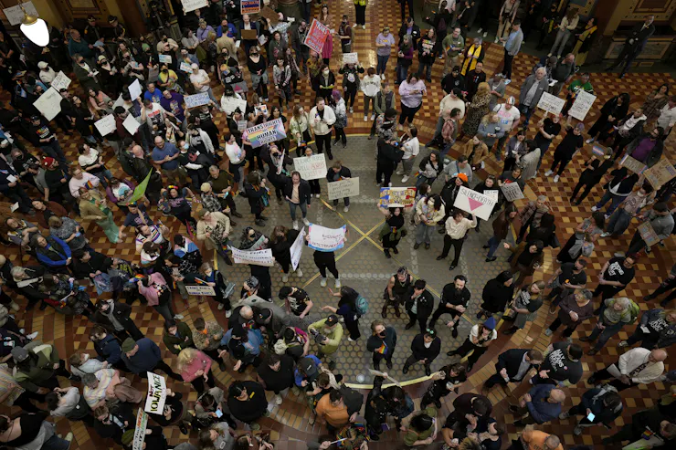 Crowd of protestors holding signs inside a capitol building