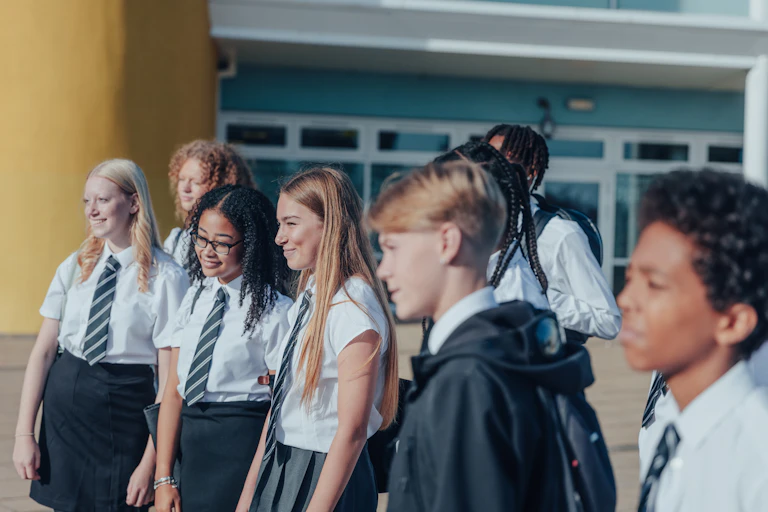 A group of high school students in uniform stand side on and smile.
