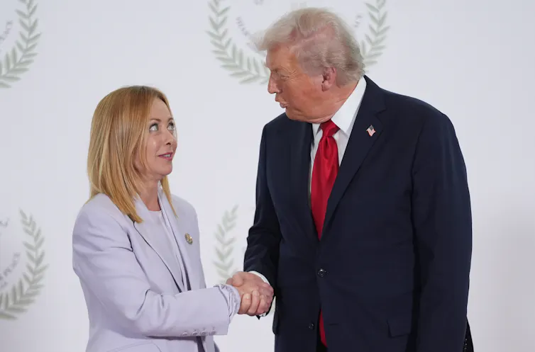 A woman with blonde hair looks up at a rotund man with greyish-yellow hair as they shake hands.