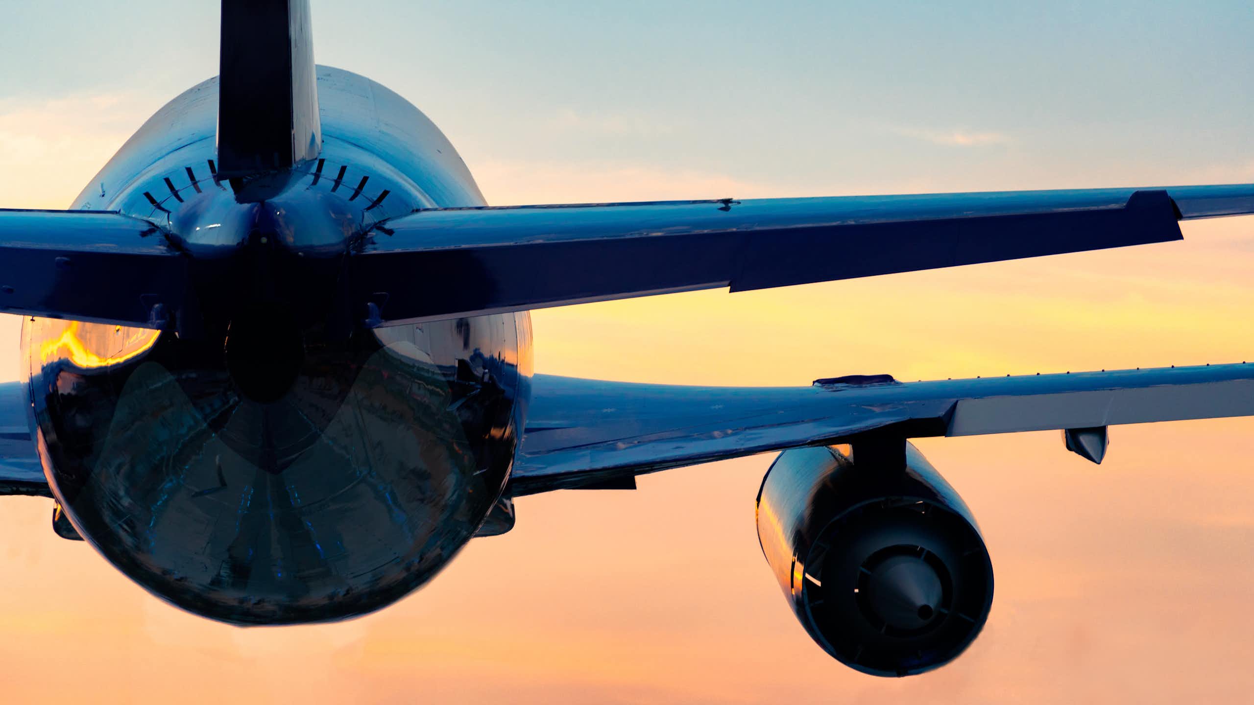 Low-angle view of a plane flying into a sunset