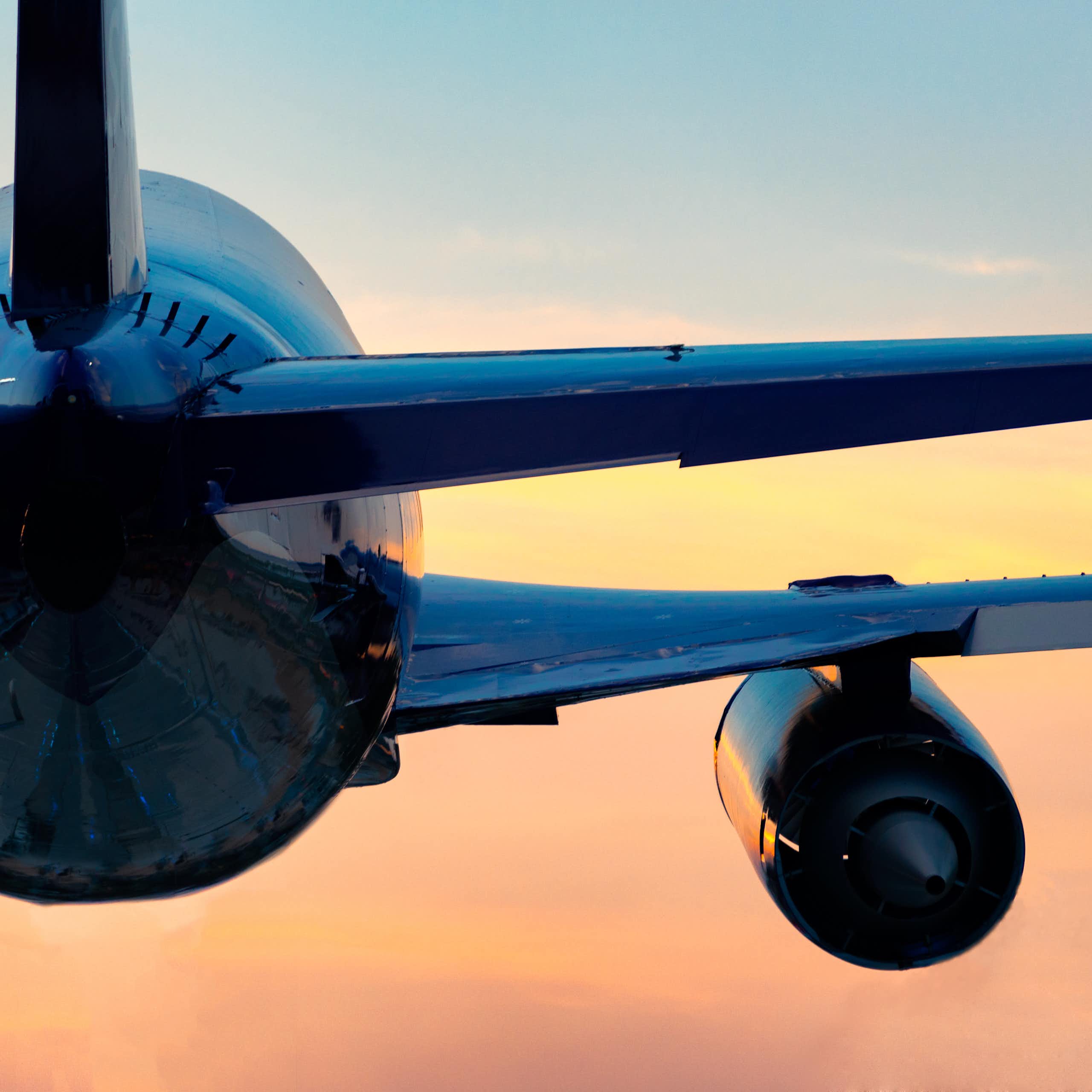 Low-angle view of a plane flying into a sunset