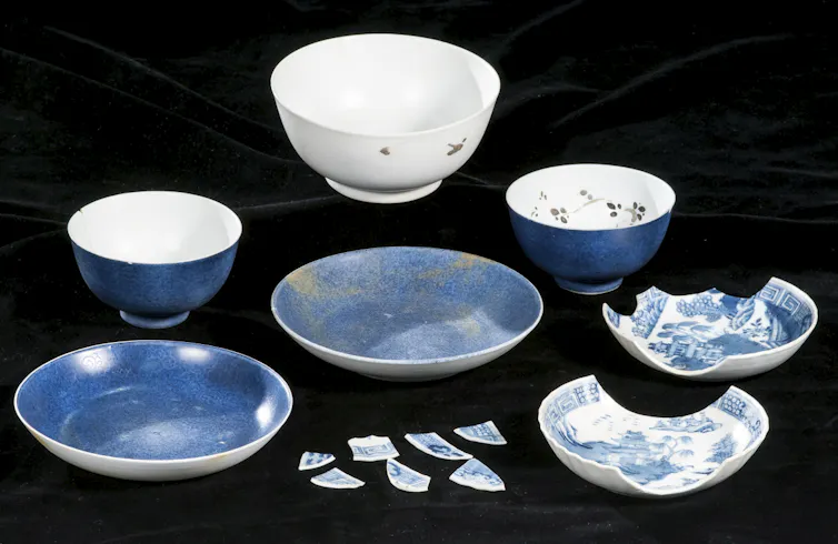 A photo of collection of old blue and white ceramics. Some have patterns, while some are broken into pieces.