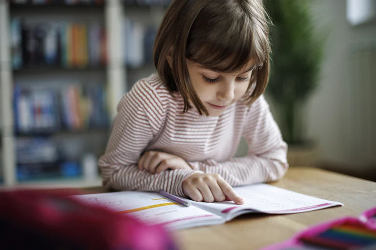 Young child reading a school work book